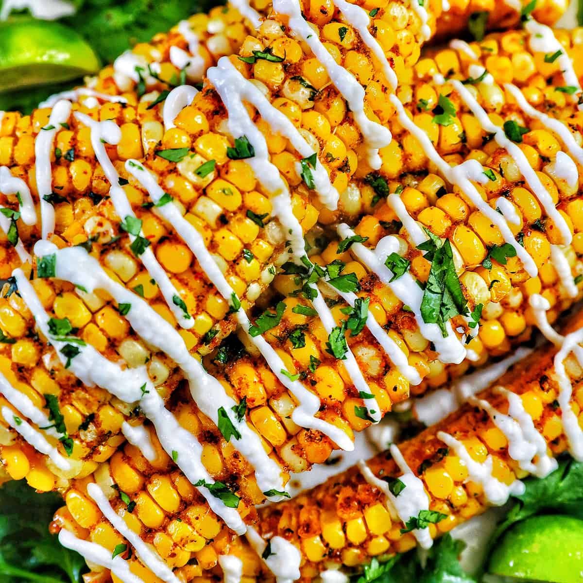 closeup photo of air fryer corn ribs stacked on top of one another with drizzled mayo and chopped cilantro.