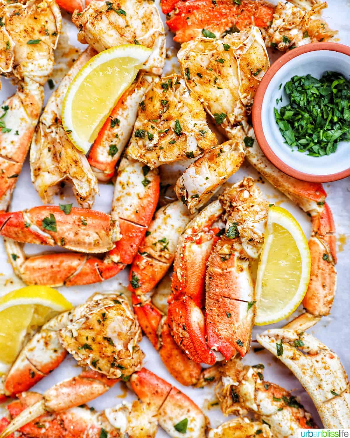 air fryer crab legs with lemon wedges and chopped parsley.
