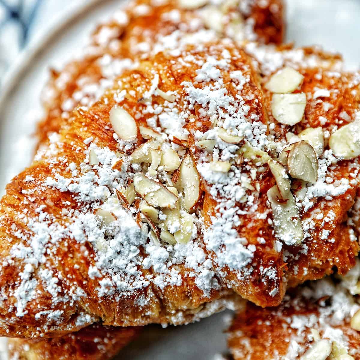 stack of almond croissants on a plate.