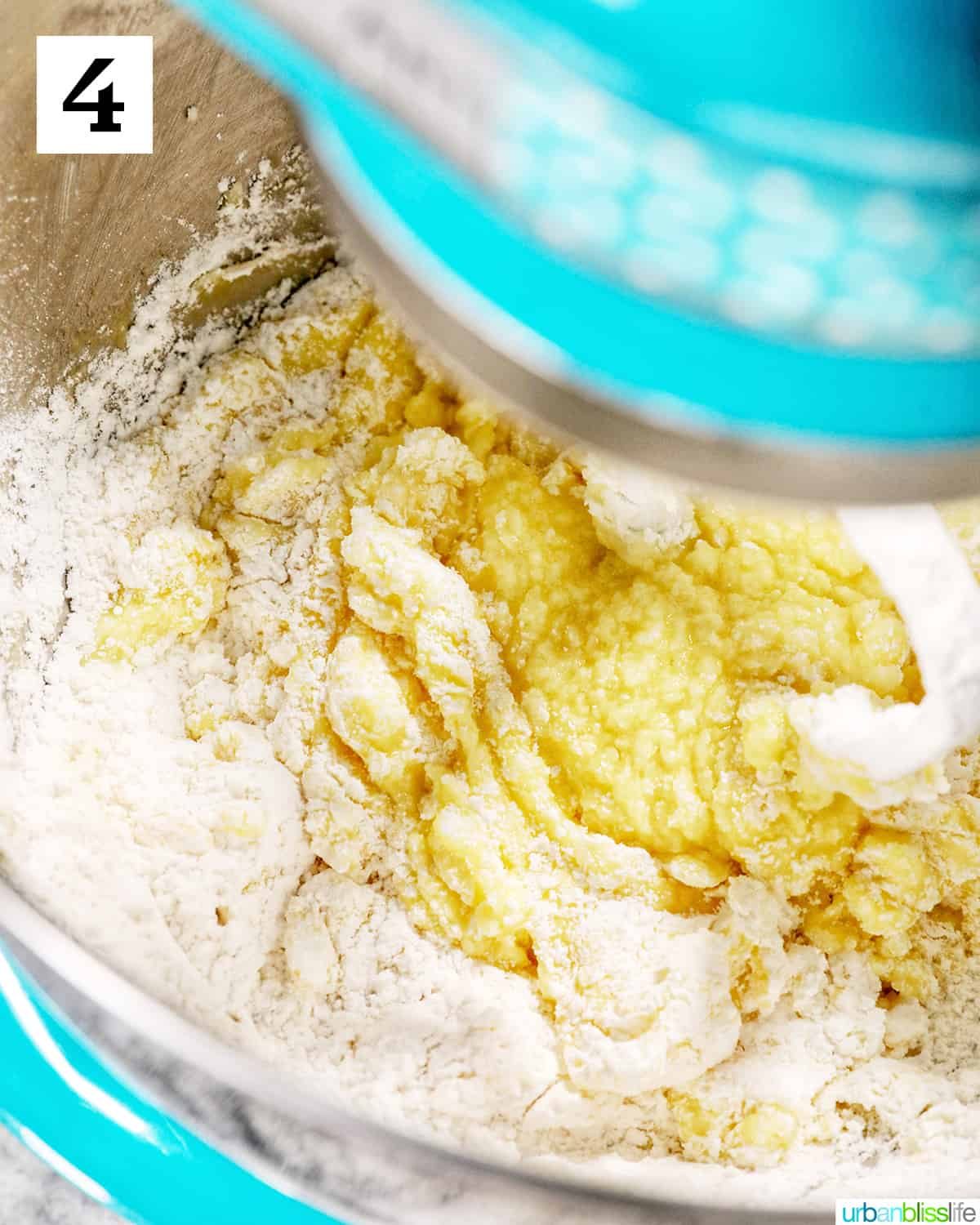adding flour to the wet ingredients in a bright blue stand mixer.