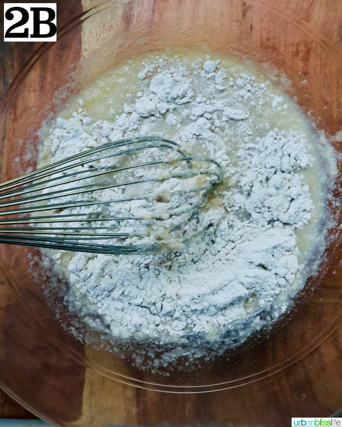 whisking in dry ingredients with wet ingredients to make apple fritters.