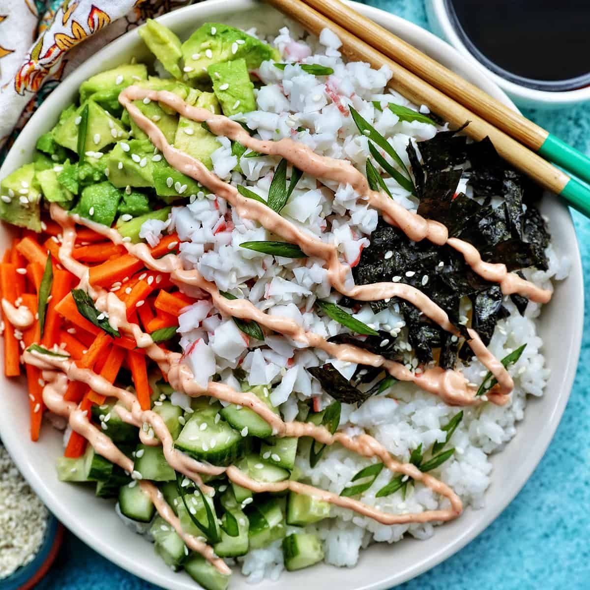Carlifornia Sushi Bowls with crab, cucumbers, carrots, avocado, nori over white rice and drizzled with a sriracha mayo.