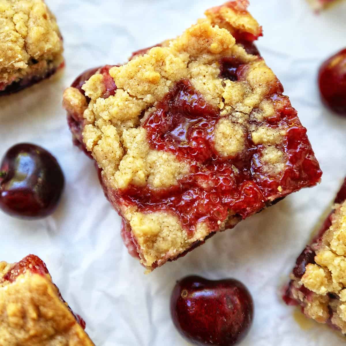 cherry crumble bars surrounded by cherries.