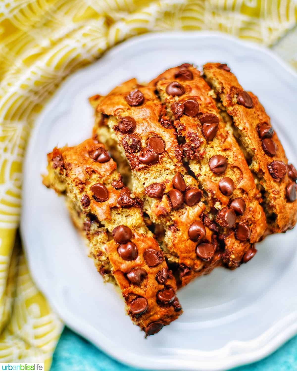 slices of chocolate chip banana bread on a white plate with yellow napkin.