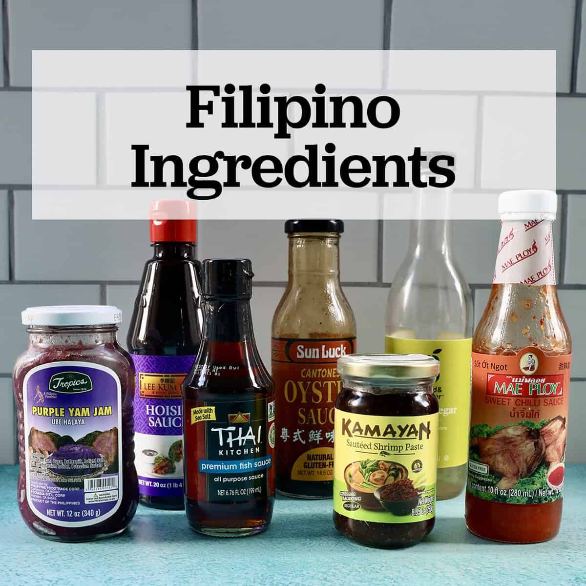 several jars and bottles of Filipino ingredients used in Filipino cuisine on a blue table with text that reads Filipino Ingredients.