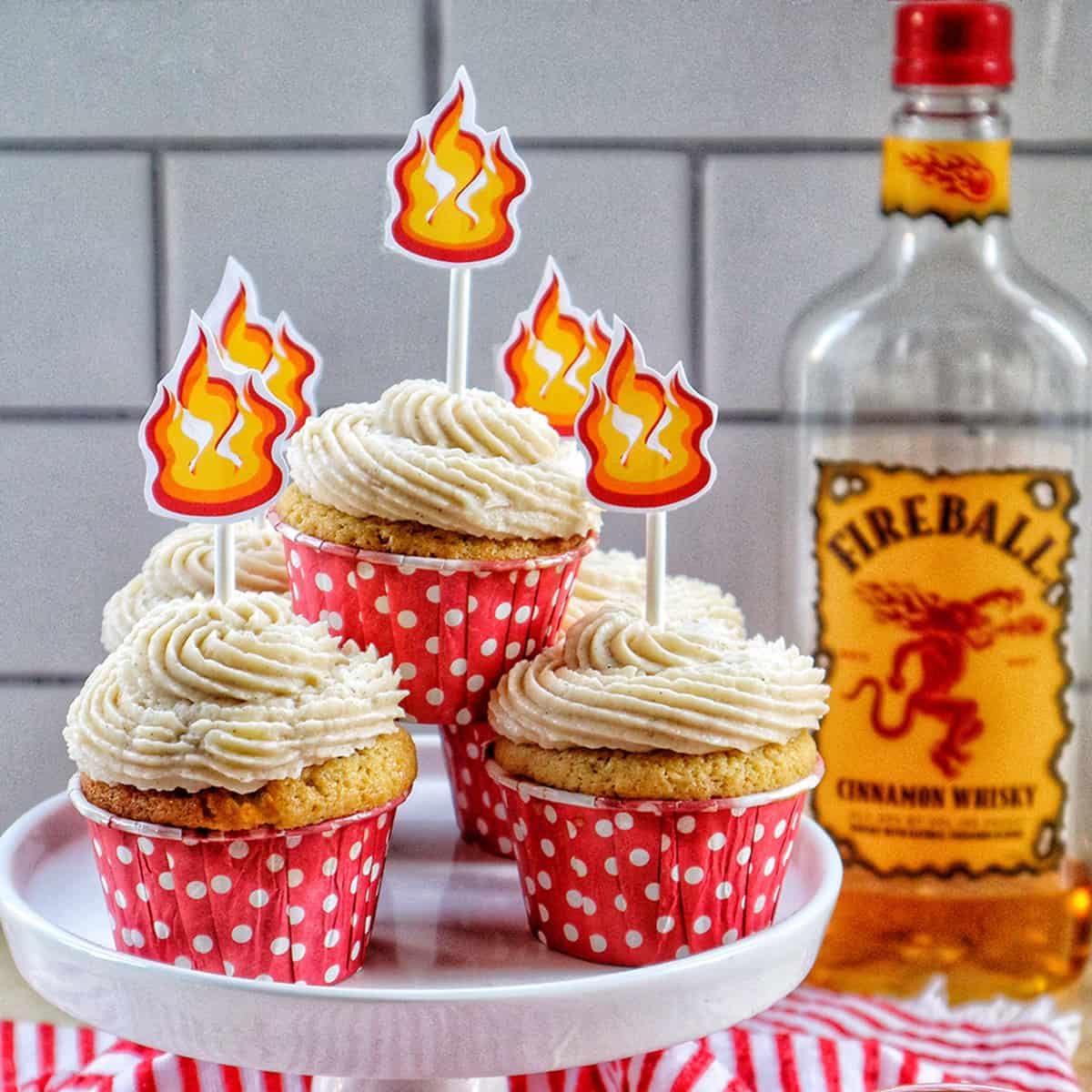 fireball cupcakes in red and white polka dot cupcake liners on a cake pedestal with buttercream frosting and fire sticker decorations on