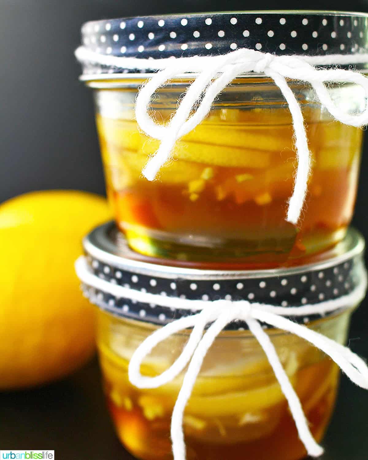 two mason jars of ginger lemon and honey marmalade stacked, with a lemon on the side.