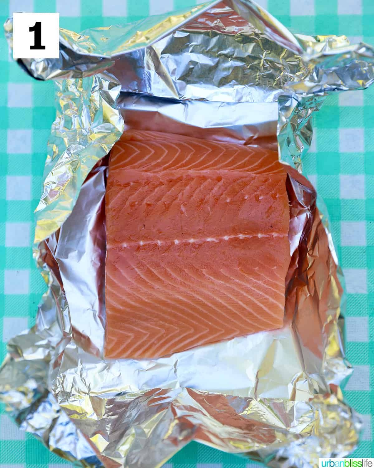 salmon filet placed in alumiinum foil on an aqua checkered tablecloth.