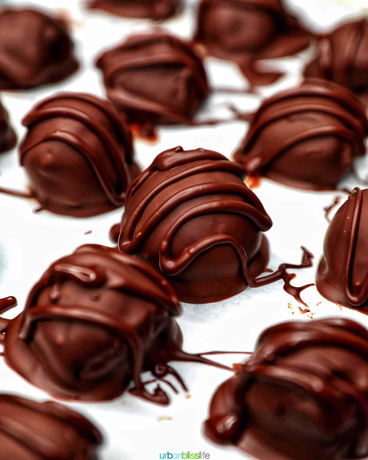 chocolate coating being drizzled onto honey bourbon truffles.