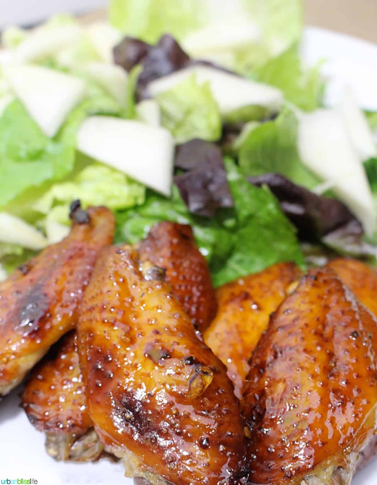 honey bourbon chicken wings next to green salad.