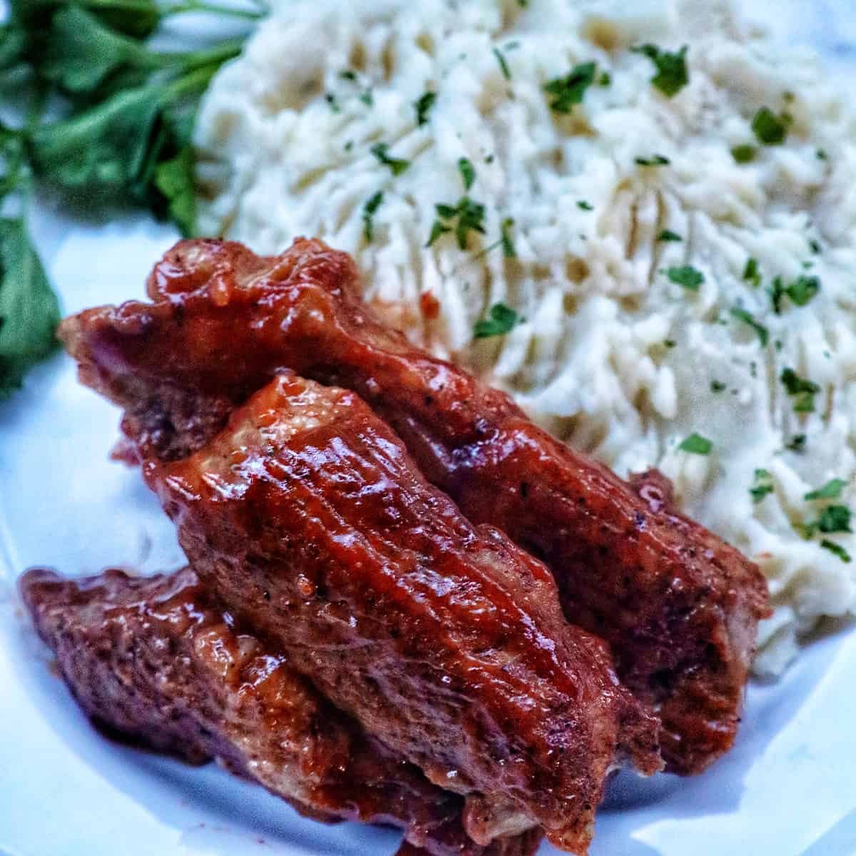 plate of Pressure-cooker country style ribs and mashed potatoes with herbs.