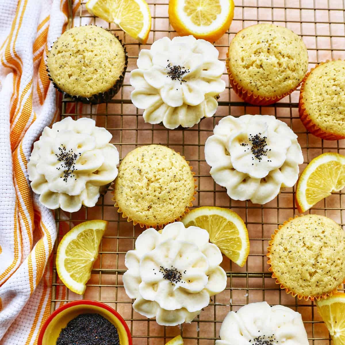 Lemon poppyseed cupcakes undecorated next to cupcakes with buttercream frosting flower decorations next to lemon slices.