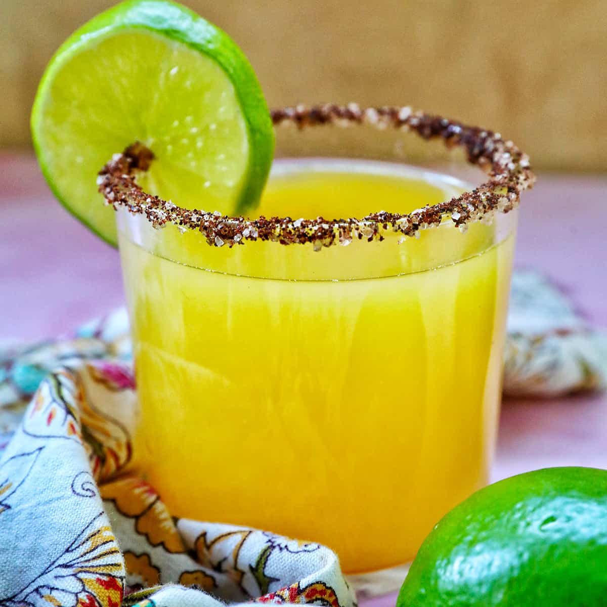 glass of spicy mango margarita with lime slice garnish and chili powder salt rim.