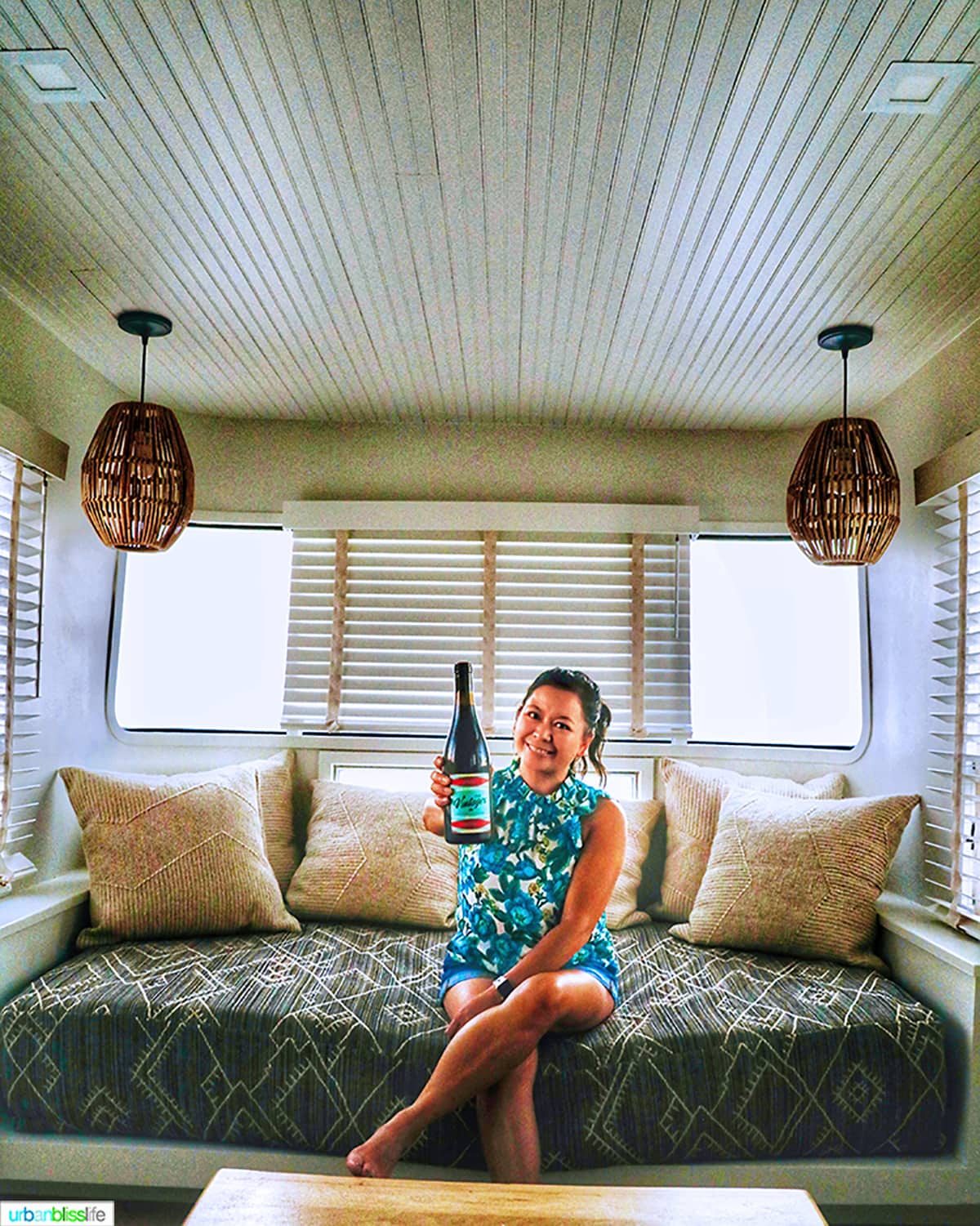 Marlynn Schotland holding up a bottle of wine inside the mansion airstream at Vintages Trailer Resort