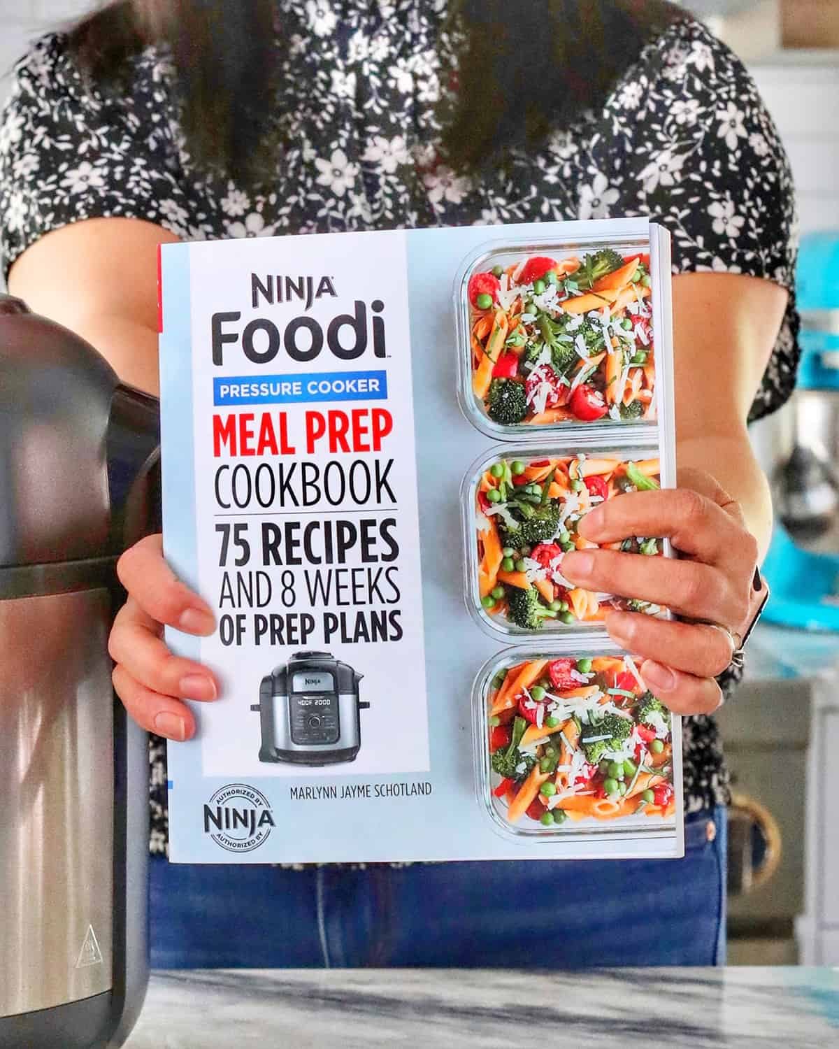 hands holding Pressure-cooker Meal Prep Cookbook
