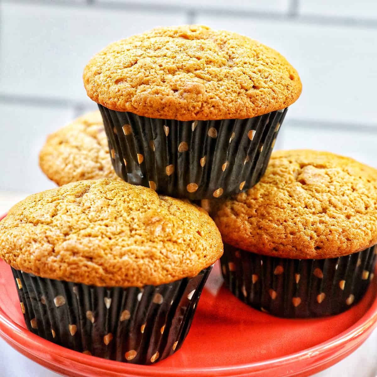 Stacks of pumpkin banana muffins on an orange plate.
