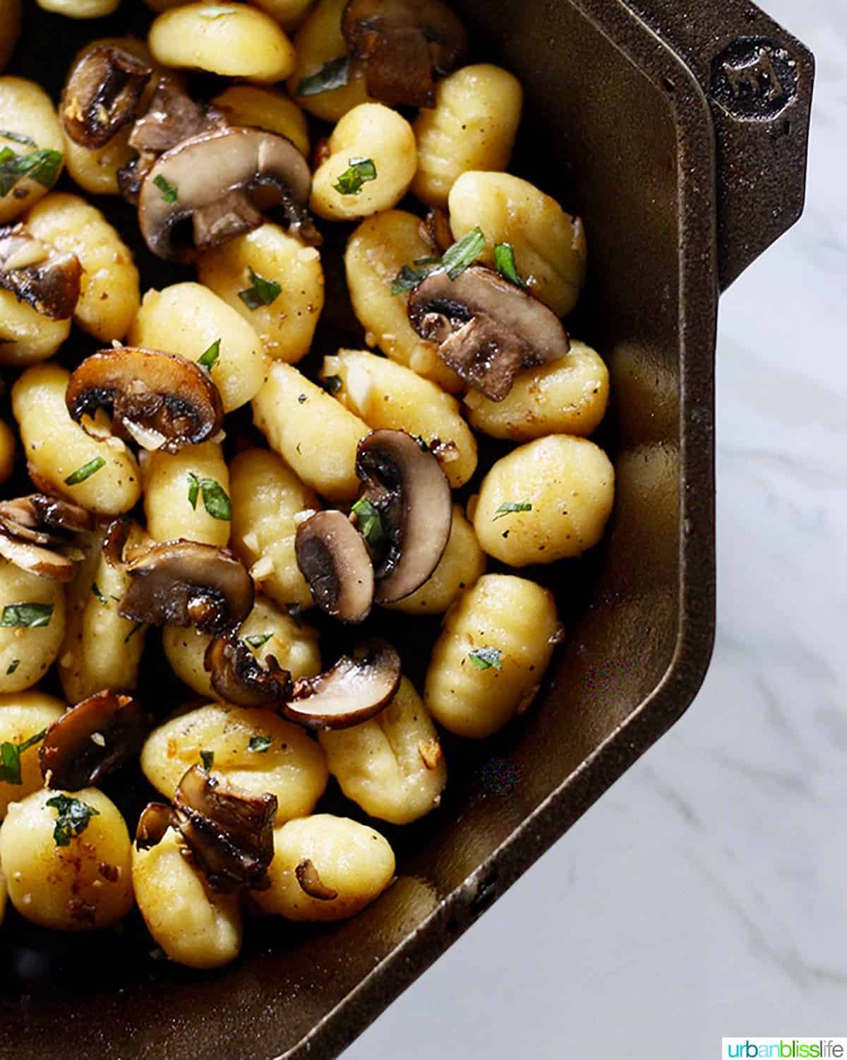 cast iron skillet with gnocchi, mushrooms, basil.