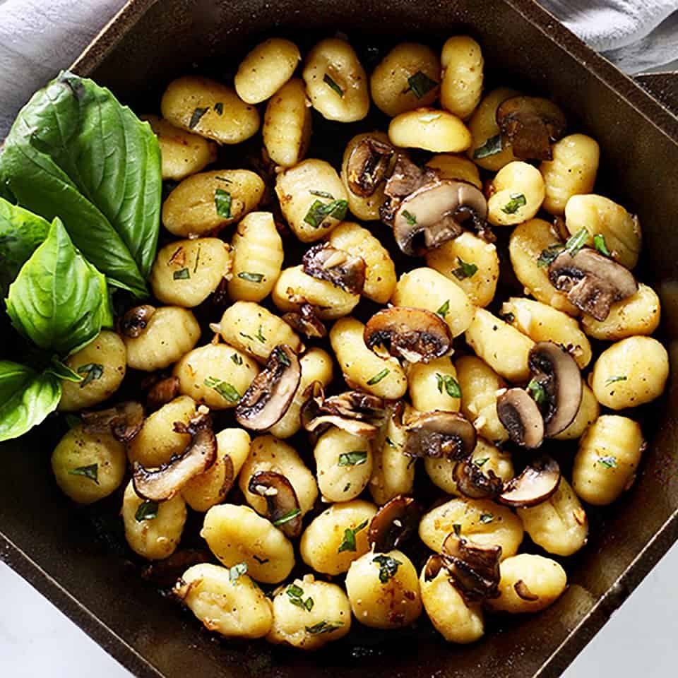 cast iron skillet with gnocchi, mushrooms, basil.