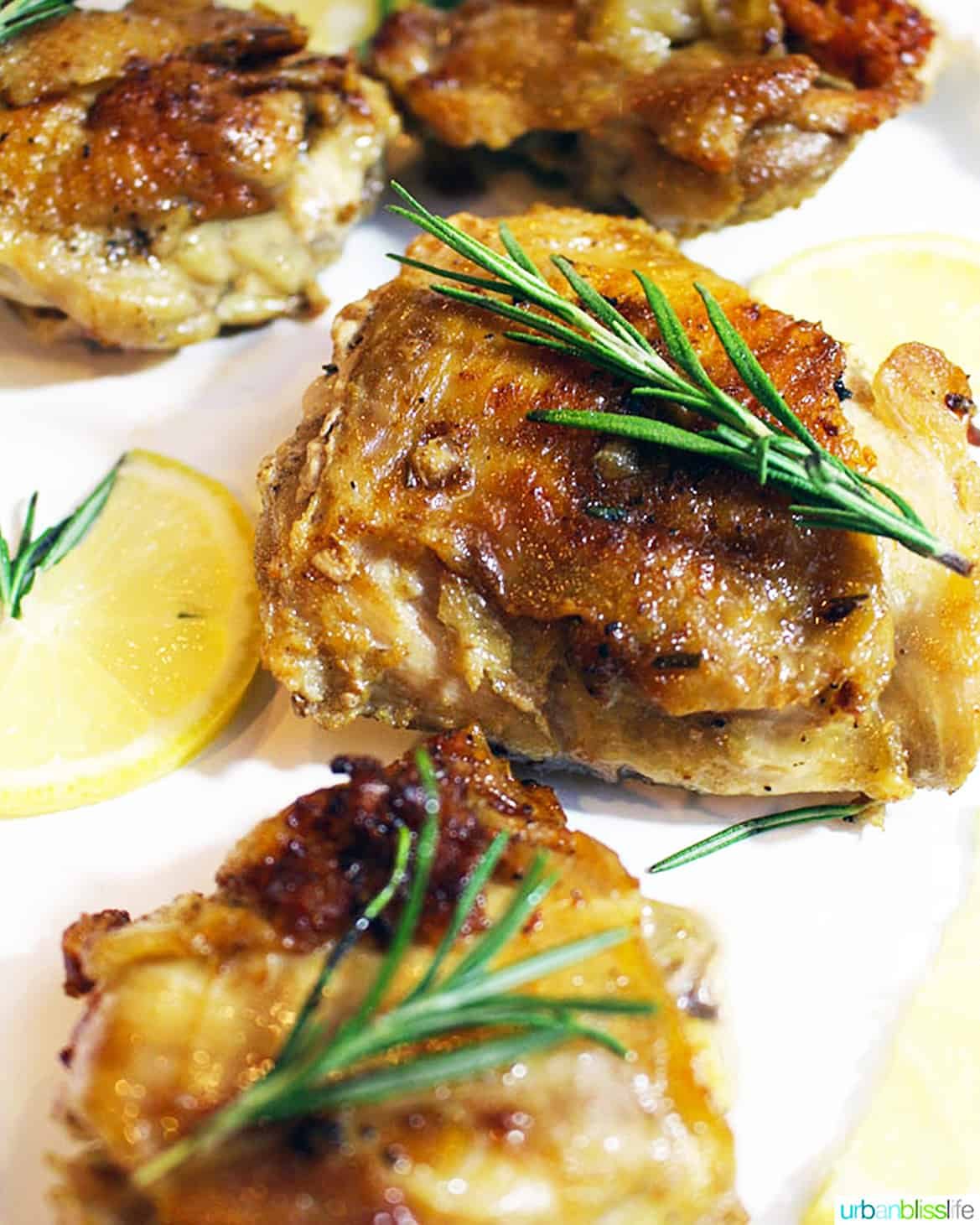 cast iron skillet chicken with rosemary sprig and lemon slices.
