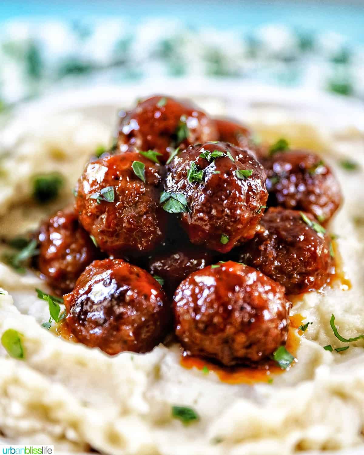 side view of slow cooker honey bourbon meatballs on a bed of mashed potatoes.