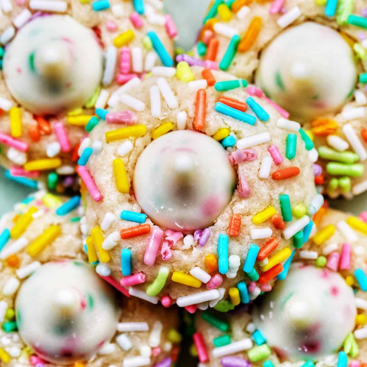several spring almond sprinkle cookies stacked on top of one another.