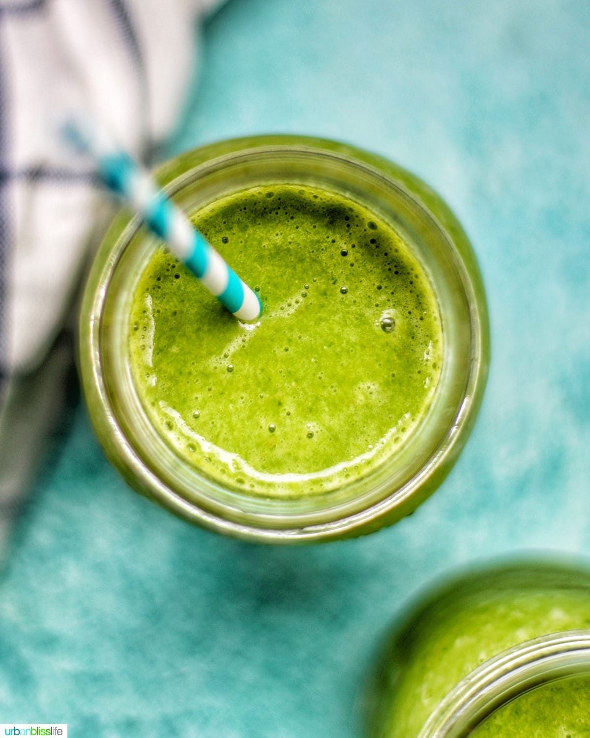 closeup looking into a mason jar with super green smoothie on a blue background