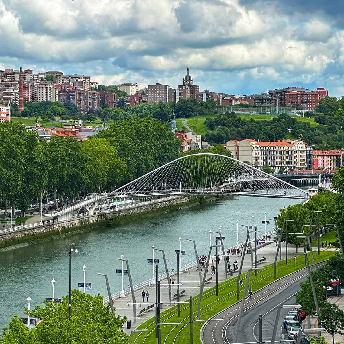 city view of Bilbao, Spain, a river, and white bridge.