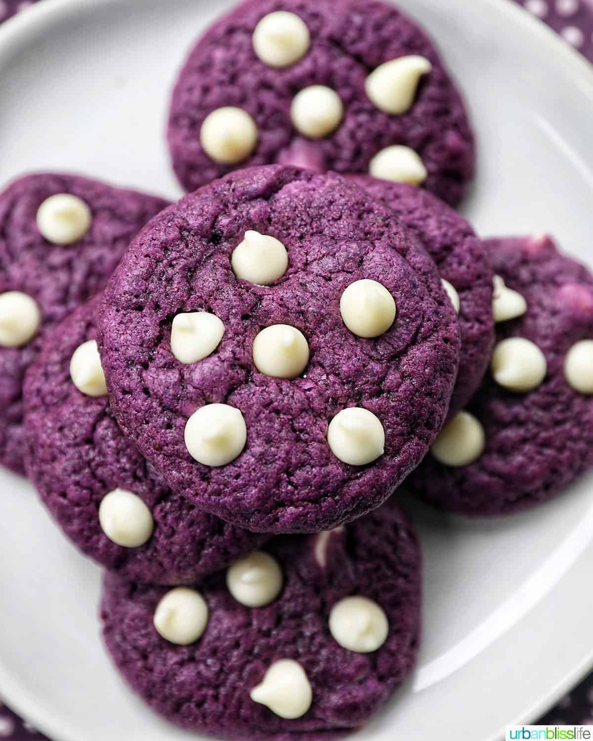 ube white chocolate chip cookies stacked on top of one another on a white plate.