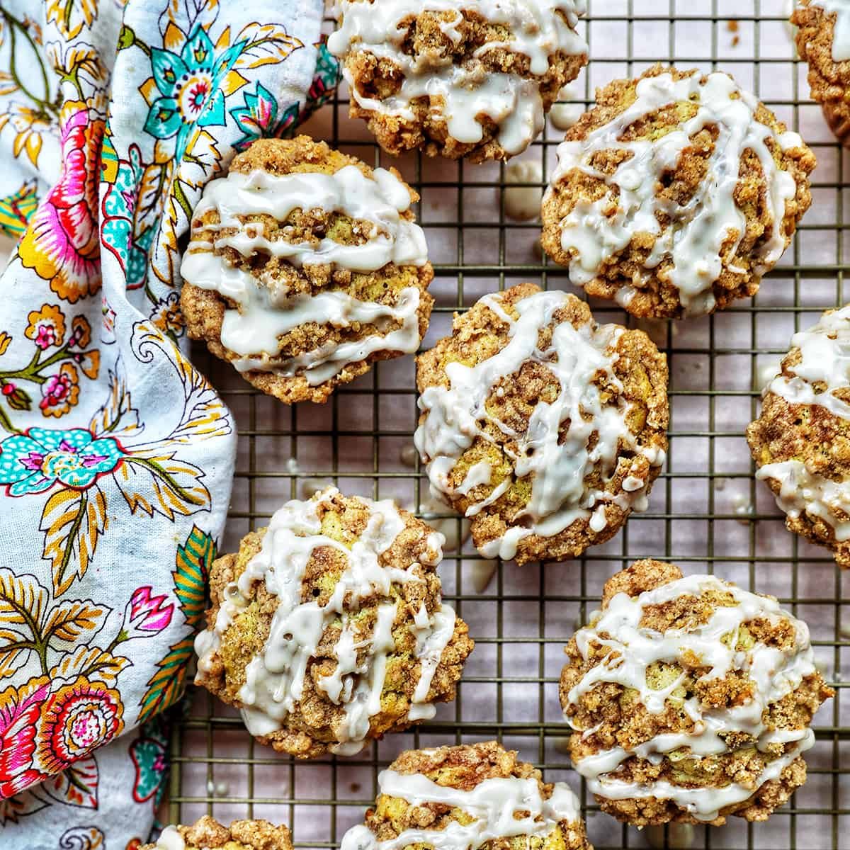 several vegan cinnamon streusel muffins on a wire rack with a colorful floral napkin.