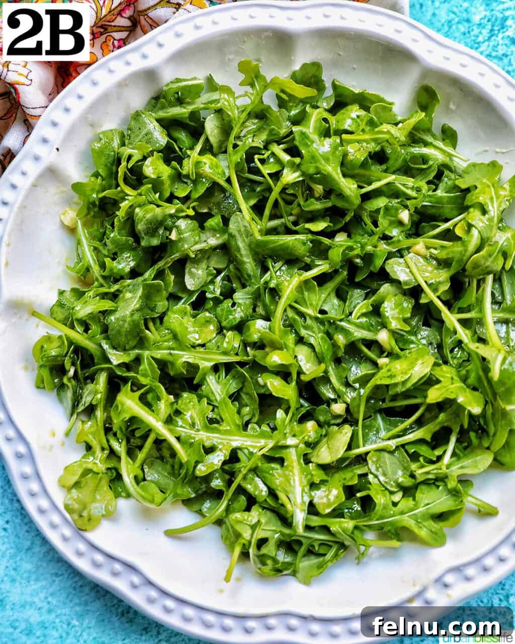 Sweet Pear and Peppery Arugula Salad 9 Baby arugula in a large white bowl, partially coated with lemon mustard dressing.
