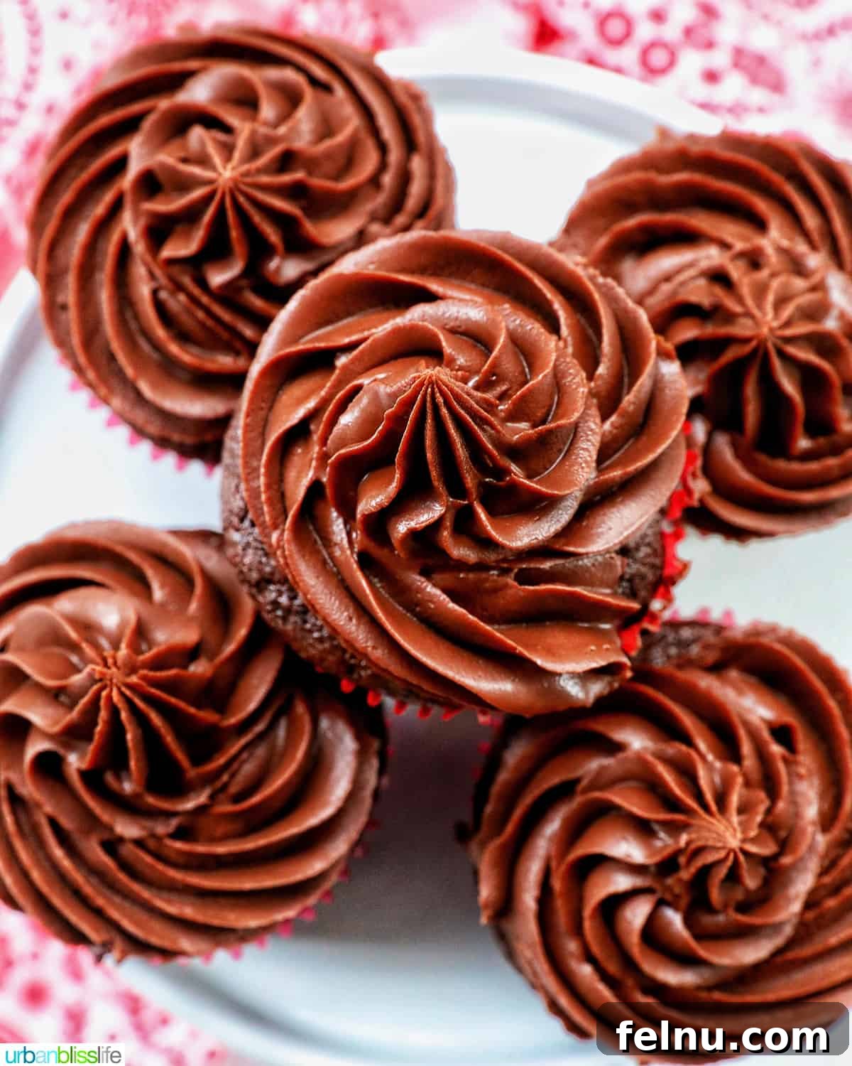 Velvet Chocolate Fudge Cupcakes 3 chocolate cupcakes with chocolate fudge frosting stacked on a cake pedestal.