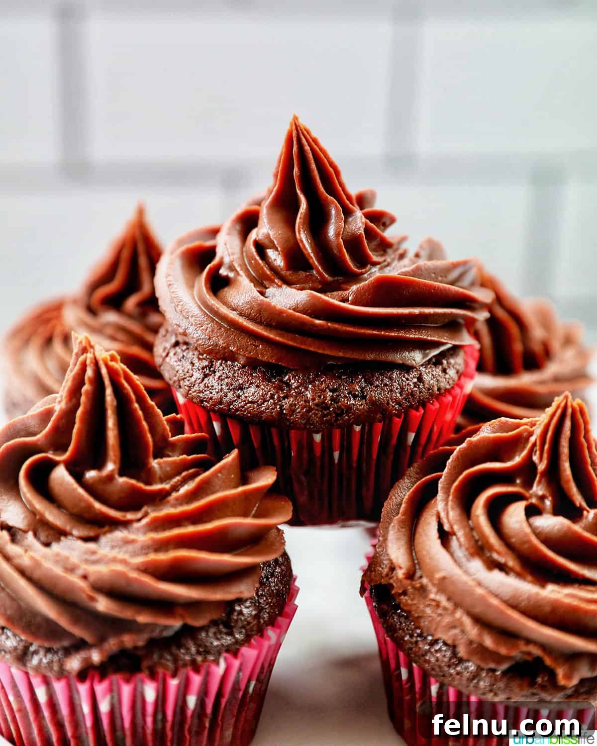 Velvet Chocolate Fudge Cupcakes 21 chocolate cupcakes with chocolate fudge frosting stacked on a cake pedestal.