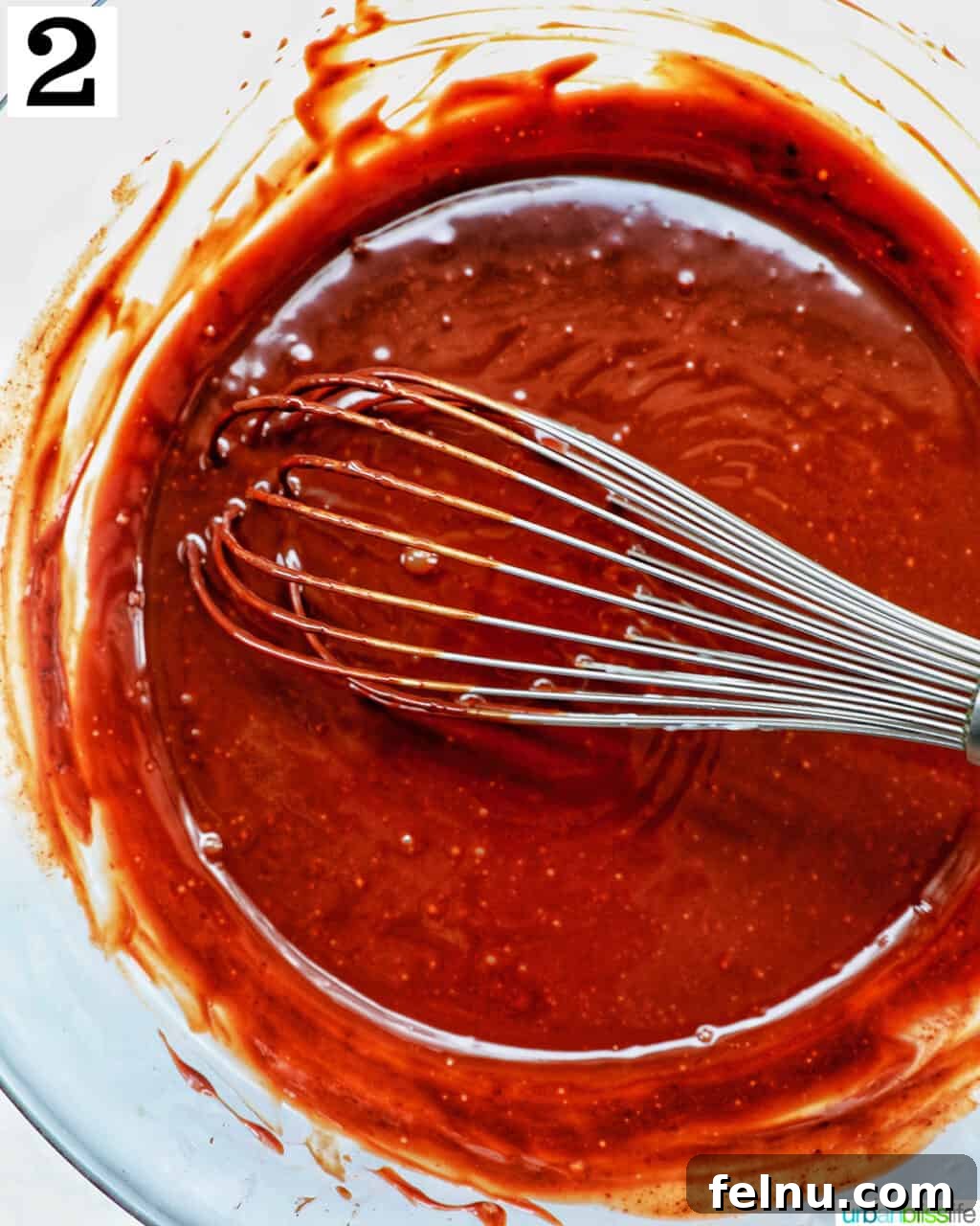 Velvet Chocolate Fudge Cupcakes 6 whisk with chocolate ganache in a bowl.