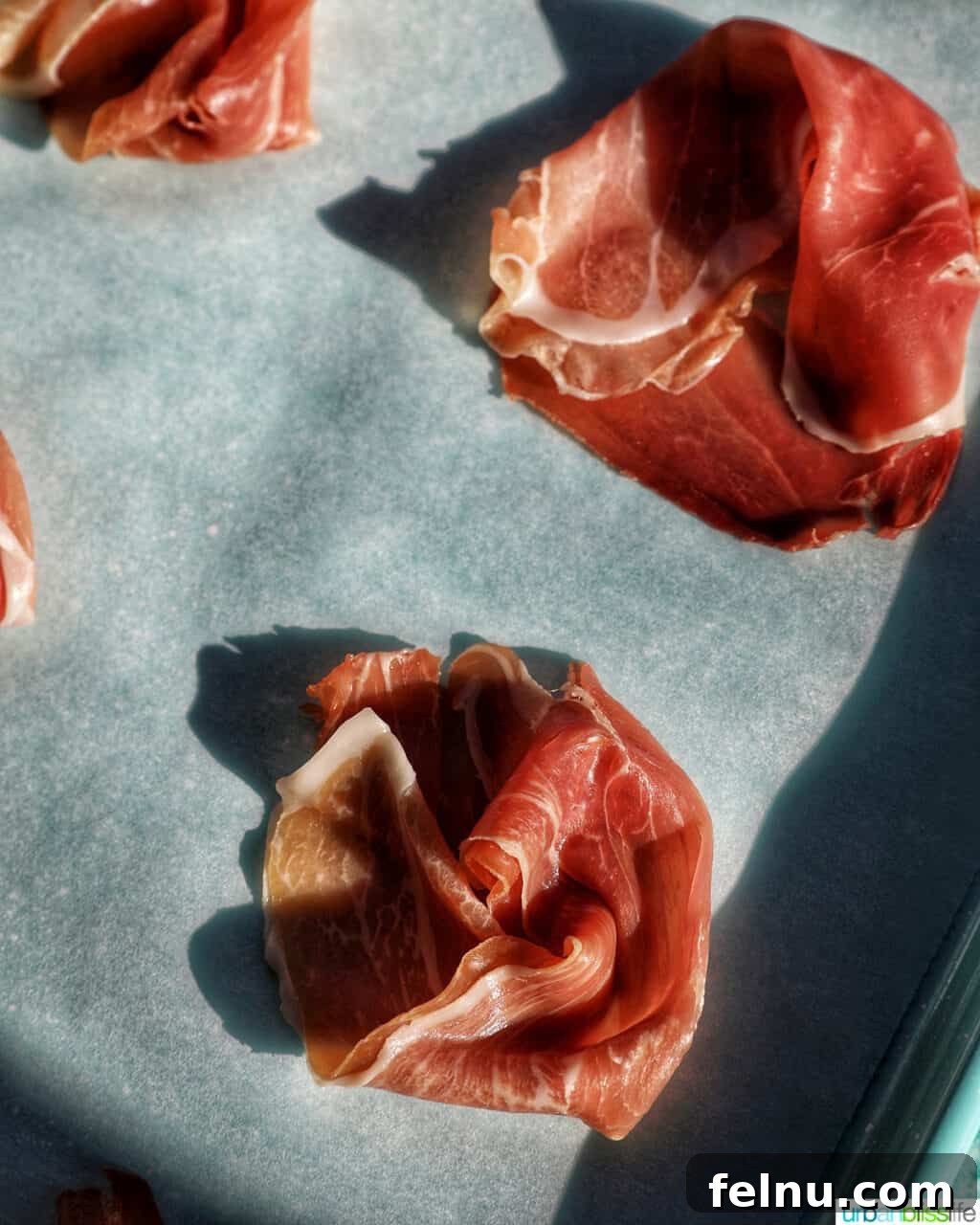 Prosciutto on a baking sheet before baking.