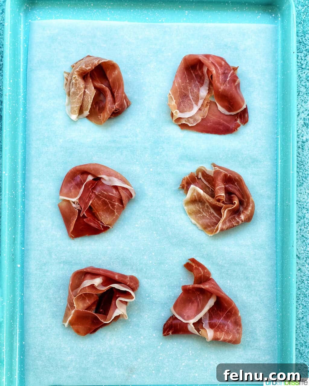 Crispy prosciutto rounds on a baking tray.