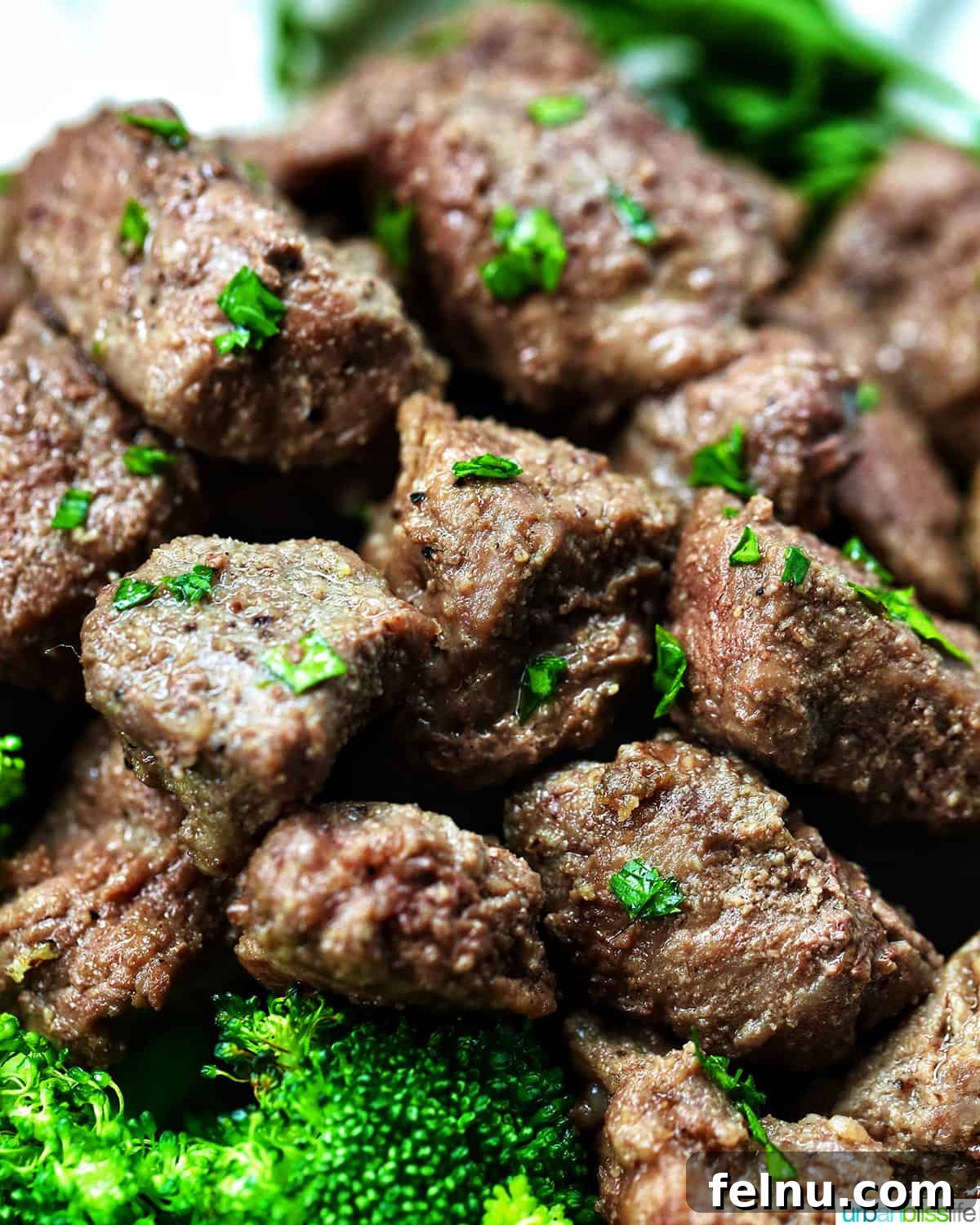 Effortless Air Fryer Steak Morsels 2 air fryer steak bites with chopped parsley garnish.