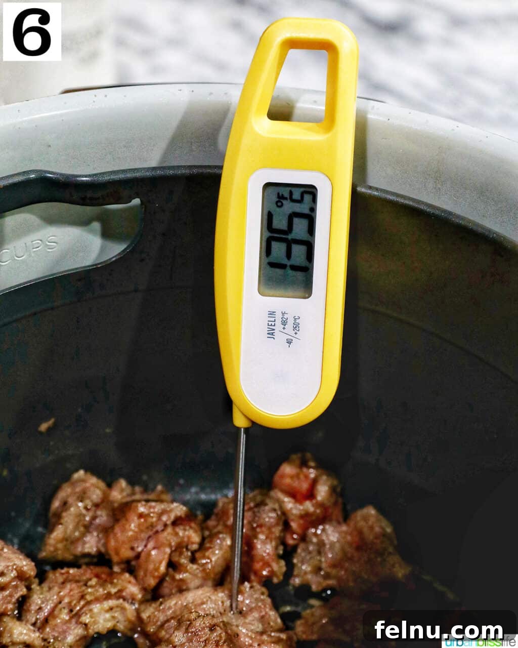 Effortless Air Fryer Steak Morsels 12 meat thermometer checking the internal temperature of steak tips in an air fryer basket.