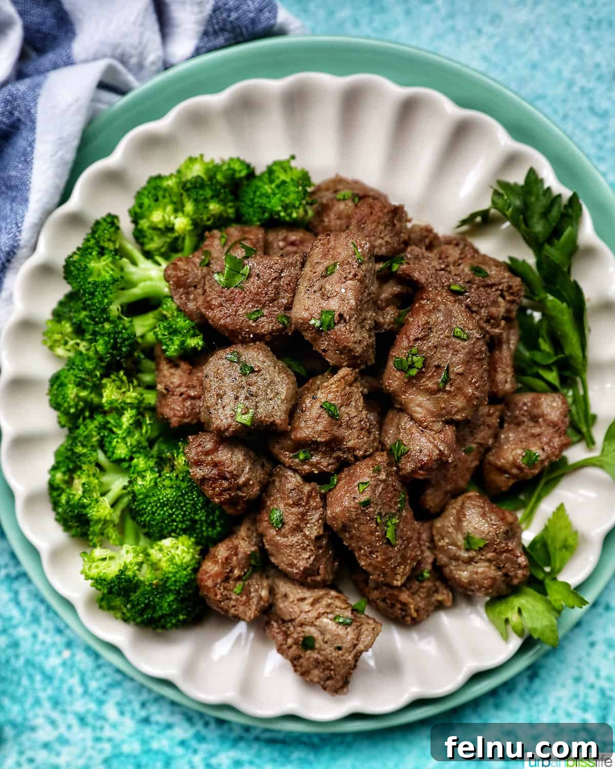 Effortless Air Fryer Steak Morsels 3 air fryer steak bites with chopped parsley garnish and a side of broccoli on a plate.