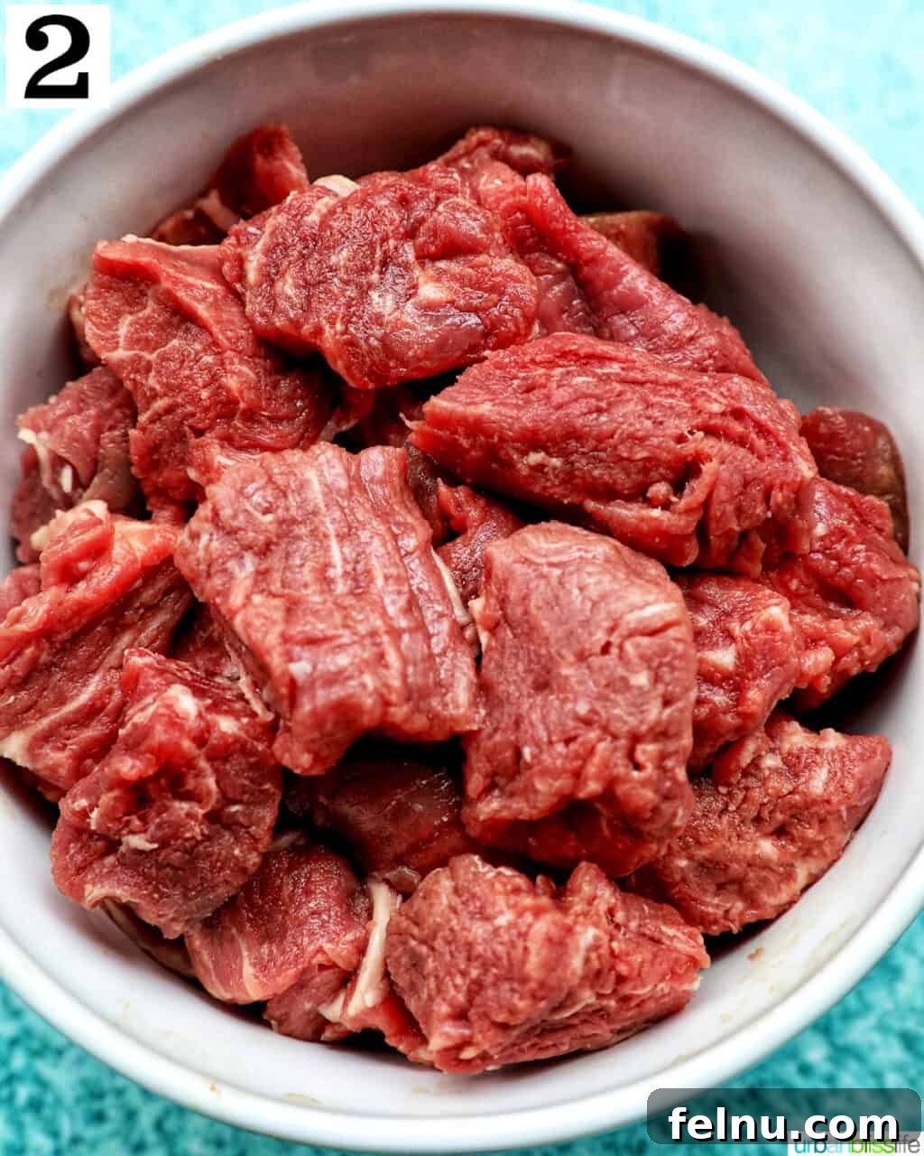 Effortless Air Fryer Steak Morsels 6 raw steak bites chopped and placed in a white bowl.