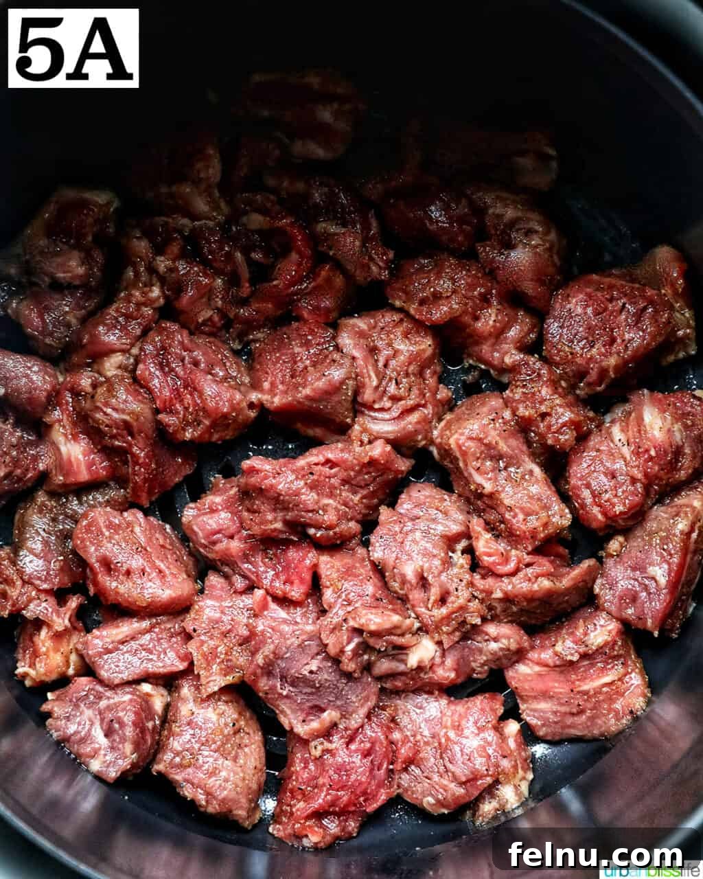 Effortless Air Fryer Steak Morsels 10 air fryer steak bites in an air fryer basket.