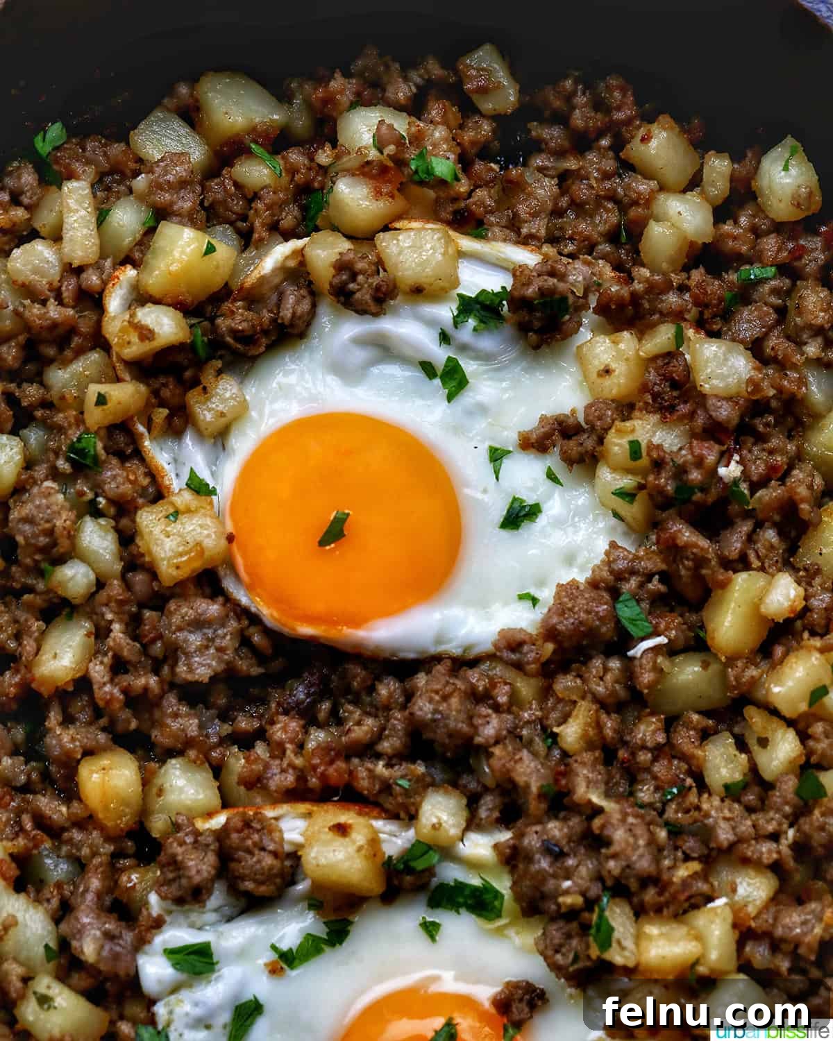 Sizzling Sausage Potato Hash 20 Breakfast sausage potato hash topped with two fried eggs, garnished with fresh parsley.