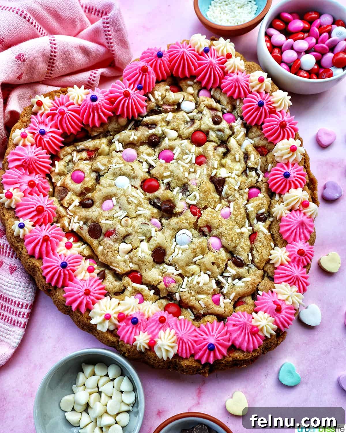 Love Struck Cookie Cake 18 A heart-shaped Valentine's Day cookie cake with pink and white vanilla frosting and red, white, and pink M & M decorations.