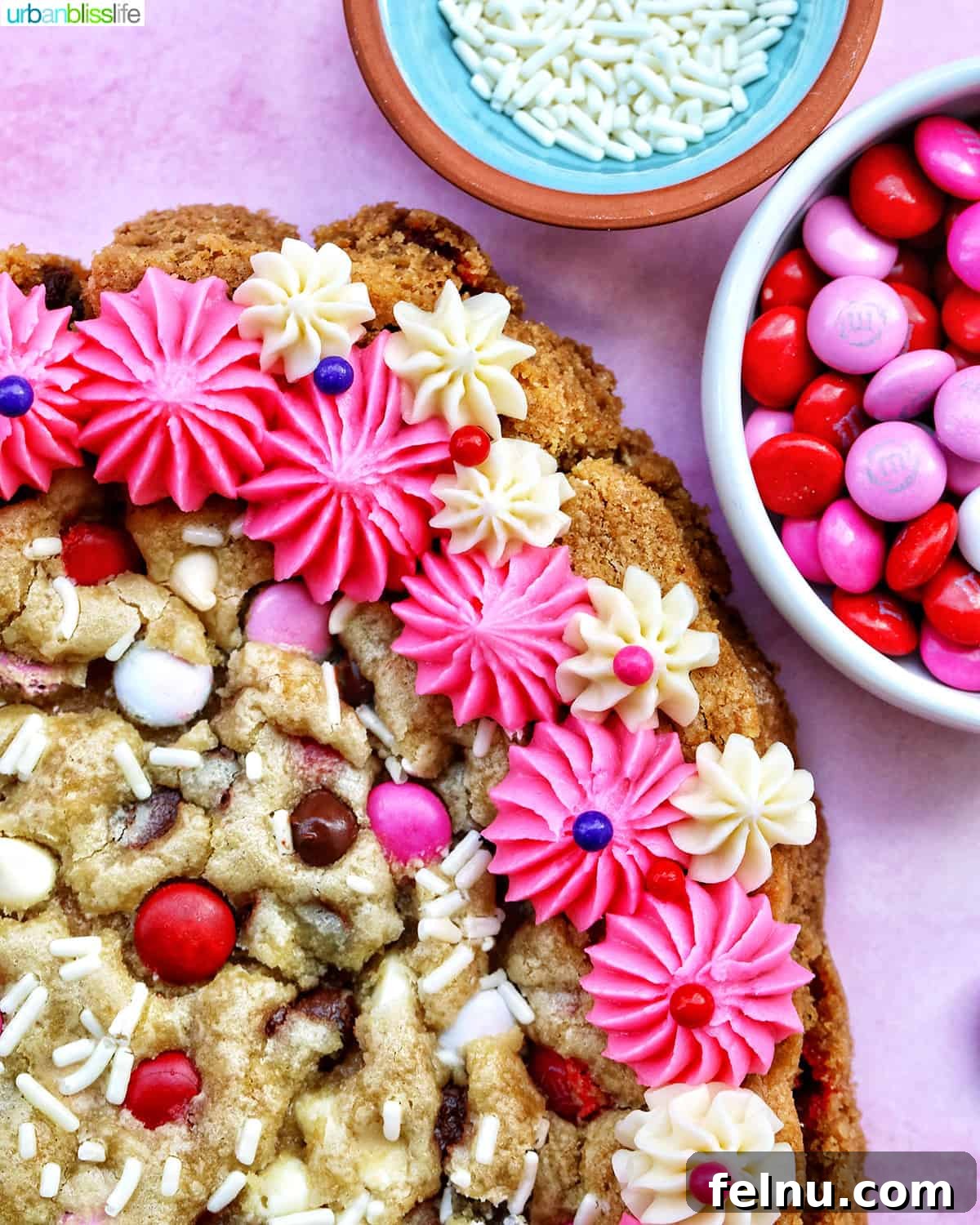 Love Struck Cookie Cake 19 A heart-shaped Valentine's Day cookie cake with pink and white vanilla frosting and red, white, and pink M & M decorations.