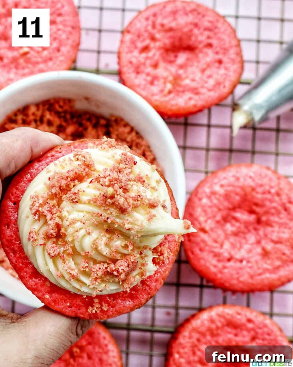 Strawberry Shortcake Crunch Cupcakes 22 Strawberry crunch topping being sprinkled over a frosted cupcake.