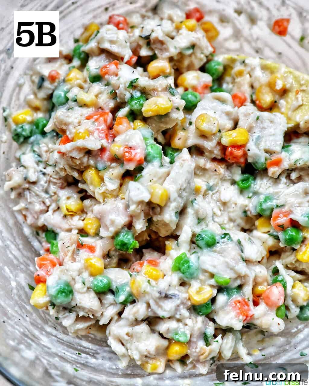 Flaky Air Fryer Chicken Pot Pie 11 shredded chicken, mixed vegetables, and fresh herbs and seasonings in a large mixing bowl.