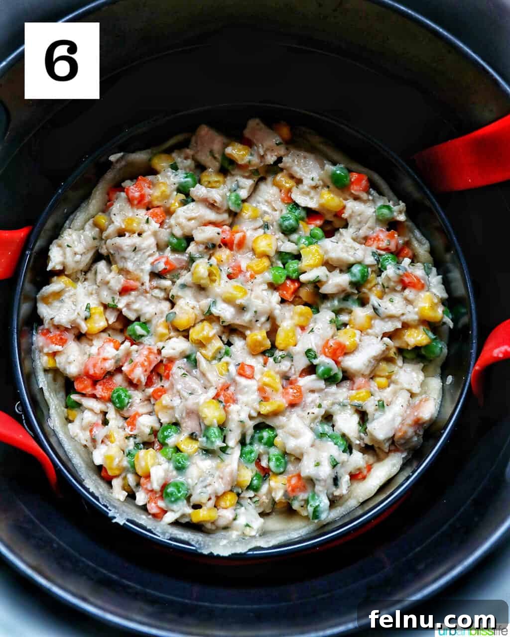 Flaky Air Fryer Chicken Pot Pie 12 shredded chicken, mixed vegetables, and fresh herbs and seasonings in a baking pan lowered into an air fryer basket.