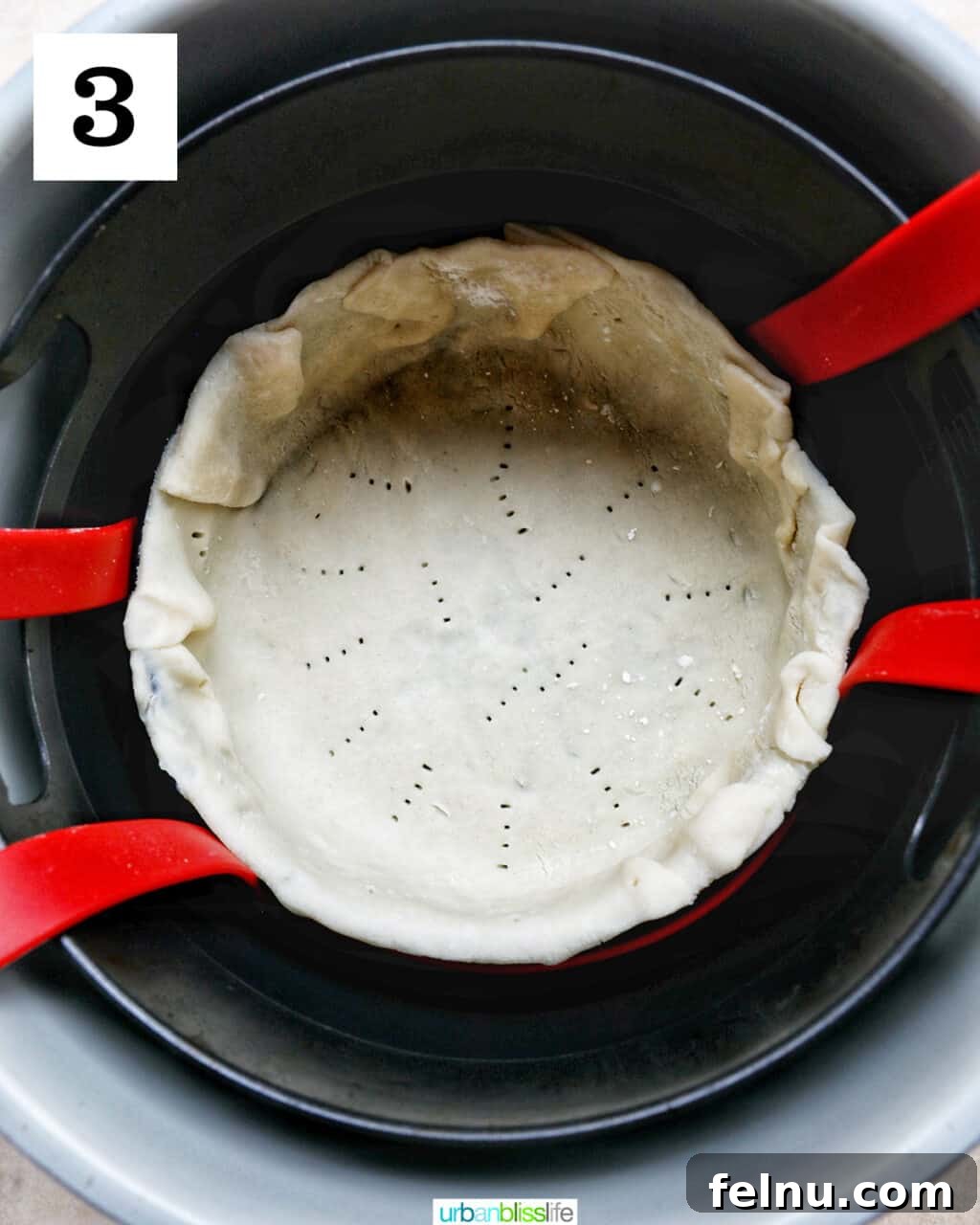 Flaky Air Fryer Chicken Pot Pie 8 unbaked pie crust in a baking pan lowered into an air fryer basket.