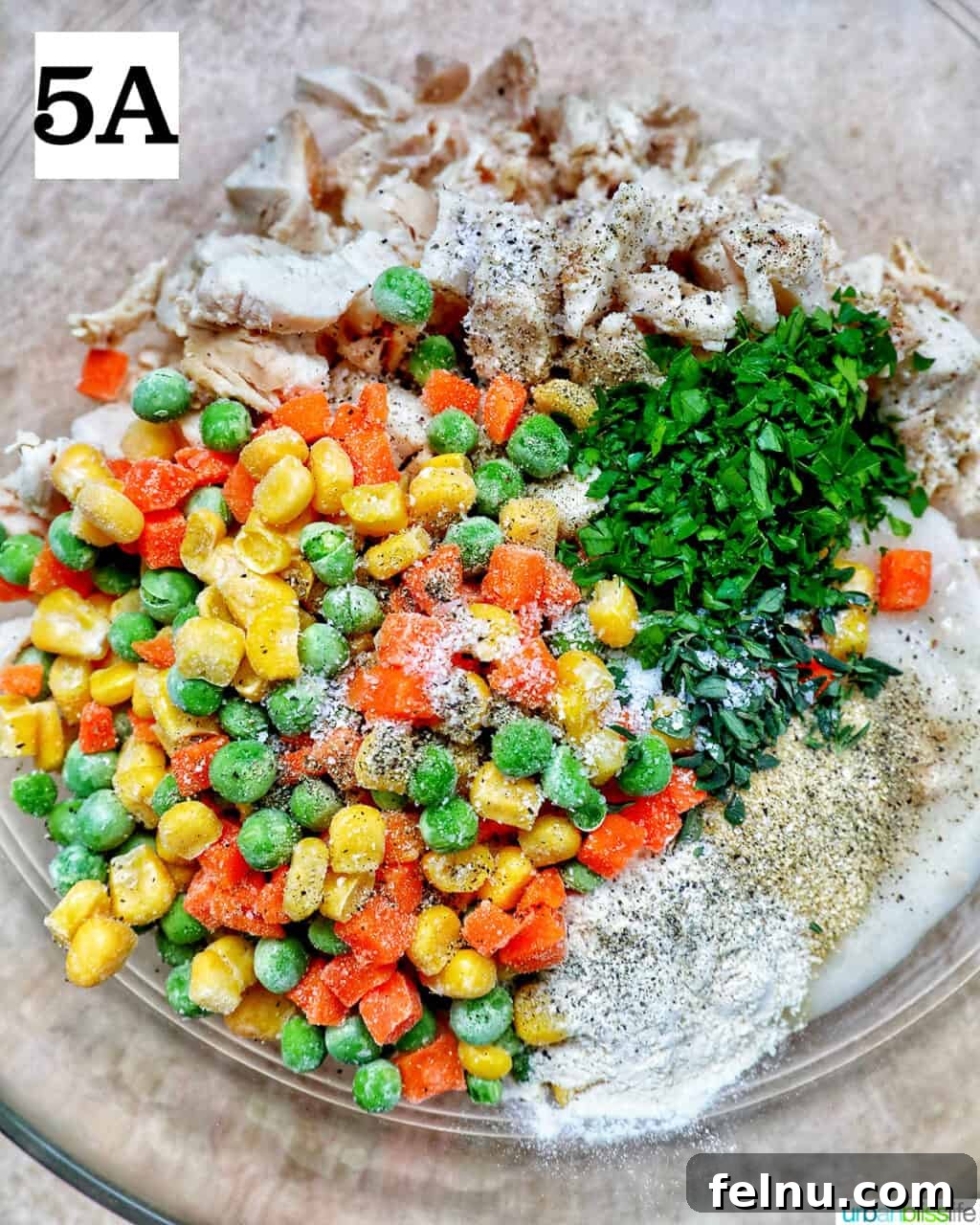 Flaky Air Fryer Chicken Pot Pie 10 shredded chicken, mixed vegetables, and fresh herbs and seasonings in a large mixing bowl.