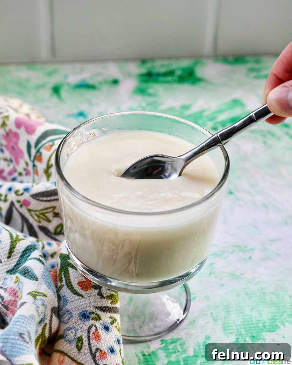 A spoonful of homemade vanilla pudding being lifted from a parfait bowl.
