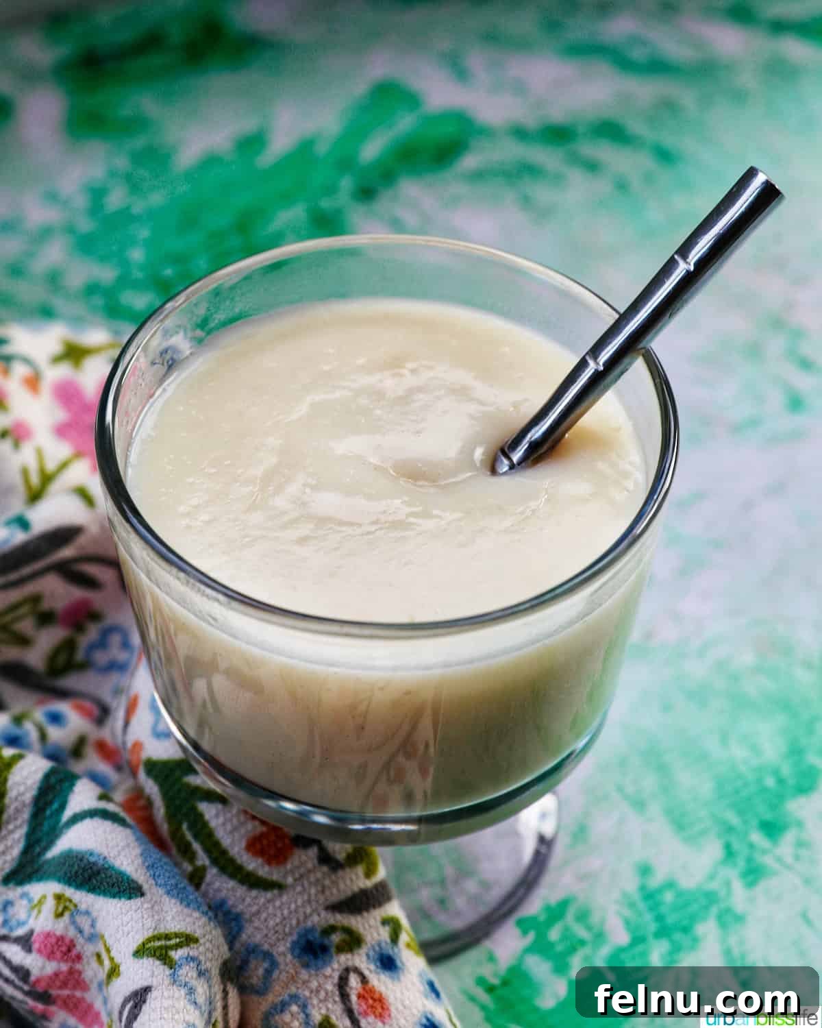 A spoonful of homemade vanilla pudding being lifted from a parfait bowl, showcasing its creamy texture.